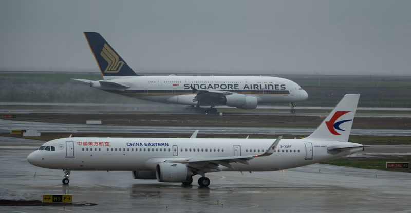 停泊在湿滑跑道上的新加坡航空与东方航空客机