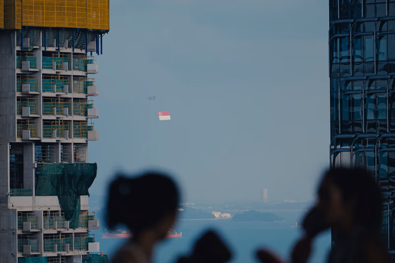 迎风飘扬的新加坡国旗，背景是拍照的人影与海景