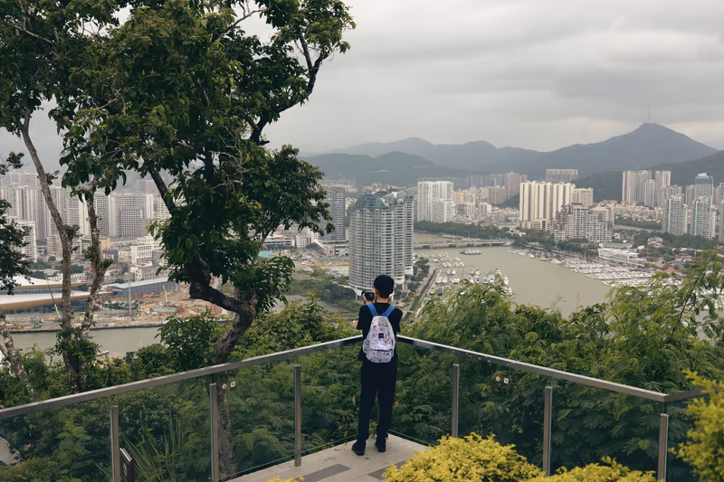 背包青年站在观景台拍摄城市全景